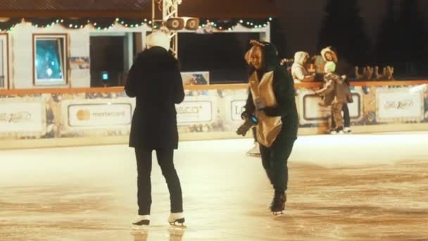 MOSCÚ - 15 DE DICIEMBRE DE 2019: Un fotógrafo con un divertido disfraz de animalito sugiere tomar una foto en una pista de hielo. Moscovitas e invitados de la ciudad montan en la pista de hielo más famosa del centro de Moscú — Vídeo de stock