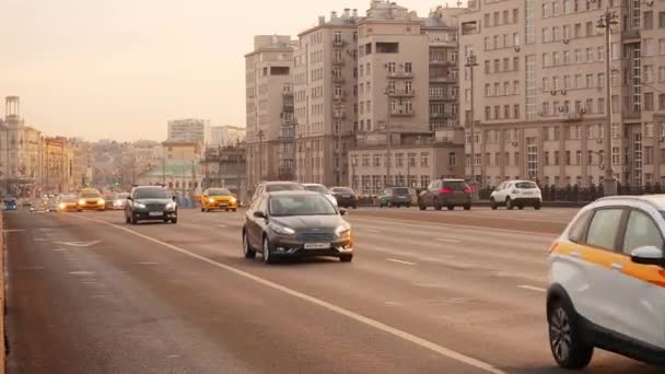 Moszkva, Oroszország - 2019. november 23.: Kilátás a Nagy Kőhídból a moszkvai Megváltó Krisztus székesegyházába a naplemente aranyidejében. Forgalom egy nagyvárosban. Az autók szélessávú mozgása — Stock videók