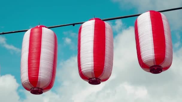 Doğulu kağıt fenerler kırmızı-beyaz Chochin beyaz bulutlu mavi gökyüzü arka planında asılı duruyor. Japon fenerleri parlak arka planda asılı. Sağa çevir — Stok video