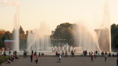 Moscow, Russia - July 21, 2019: Diversity people in the city. Adults and children rests in the park near city fountain . Citizens of Moscow have a summer rest in a summer park near the water during