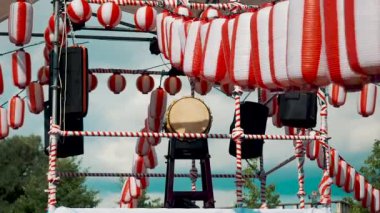 Geleneksel Japon Taiko davuluyla Yagura sahnesi. Birçok kağıt kırmızı-beyaz fener Chochin rüzgarda sallanıyor beyaz bulutların arkasında. Tatil için manzara.