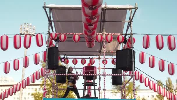 Moscú, Rusia - 16 de julio de 2017: Muchacha músico golpea el tambor taiko en la escena yagura durante el festival japonés. El escenario de la Yagura con una chica baterista gran tambor chu-daiko japonés. Papel rojo-blanco — Vídeos de Stock