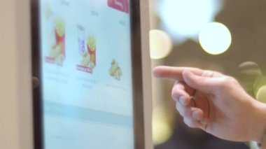 Moskova, Rusya - 16 Mart 2019 McDonalds 'da fast food seçimi. Kafası karışmış bir adam hangi yemeği seçeceğini düşünüyor. Bir adam sipariş vermek için büfe kullanarak patates kızartması alıyor. self servis sıralaması