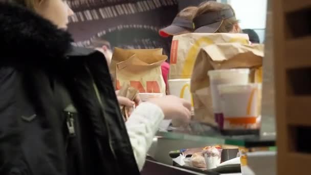 Moscú, Rusia - 15 de diciembre de 2019: Los clientes reciben su pedido de comida para llevar en el área de emisión de pedidos en el restaurante McDonalds. Contador de servicio en un McDonalds. Gerentes amistosos de McDonald — Vídeos de Stock