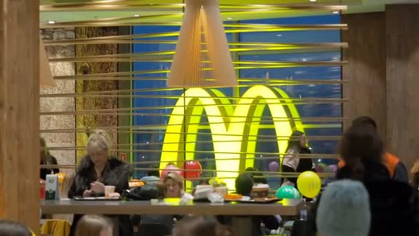 モスクワ、ロシア- 12月15 、 2019:マクドナルドのシンボルとしての大きな黄色の発光文字Mは多くの人々とレストラン内で成長します — ストック動画