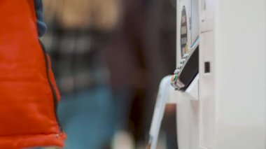 İnsan akıllı telefonu self servis terminaline bağlar. Adam NFC ödemesini kullanarak internetten alışveriş yapıyor. Adam cep telefonuyla NFC ile internet üzerinden ödeme yapıyor..