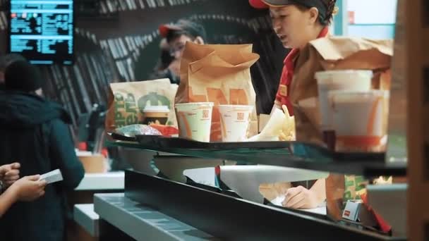 Moscovo, Rússia - 15 de Dezembro de 2019: Clientes à espera de comida na área de emissão de encomendas no restaurante McDonalds. Contra-serviço num McDonalds. Um amigável gestores de — Vídeo de Stock