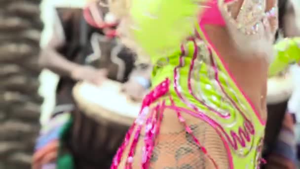 MOSCÚ, RUSIA - 29 de FEBRERO de 2020: Hermosa chica brillante traje de carnaval colorido decorado con pedrería bailando samba. Bateristas africanos con ropas étnicas tocando el tambor djembe de cerca — Vídeos de Stock