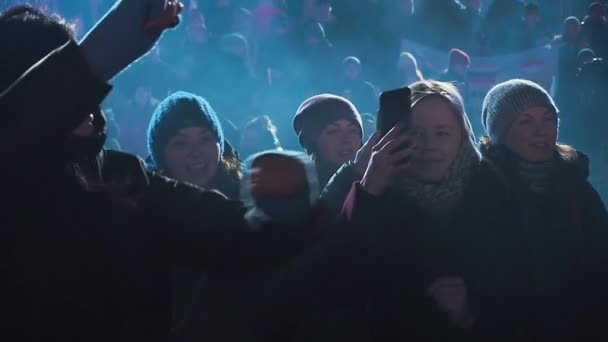 Москва, Россия - 15 февраля 2020 года: Красивая брюнетка танцует в толпе на концерте. Её подруга ведёт прямую трансляцию концерта в социальных сетях. Красивая кавказская девушка танцует на концерте в — стоковое видео