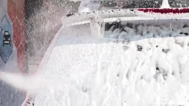 Slow Motion Video av biltvätt processen på en självbetjäning Car Wash. En vattenstråle med en hög högtryckstvätt bort skummet från fönstret bil bakre — Stockvideo