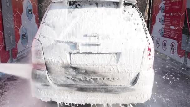 MOSCÚ, RUSIA 25 DE MARZO DE 2019: Vídeo en cámara lenta del proceso de lavado de autos en un lavado de auto-servicio. Un chorro de agua con un lavado de alta presión de la espuma desde la parte posterior del automóvil y la ventana trasera — Vídeo de stock