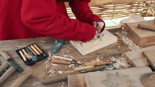 Ένας τεχνίτης σκάλισε ένα ταψί μελόψωμο και μπισκότα από ξύλο με μαχαίρι. Ο ξυλουργός κάνει ξυλόγλυπτα. Λεπτομέρεια από χέρια εργασίας. Ο γλύπτης φτιάχνει το γλυπτό. Παραδοσιακό σκάφος — Αρχείο Βίντεο