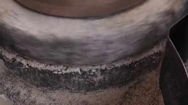 Tahıllı antik quern taş el değirmeni. Adam bir değirmen taşının yardımıyla tahılı un haline getiriyor. İnsan eliyle döndürülmüş eski öğütme taşları. Miller tahılı bir taş değirmenine döküyor..