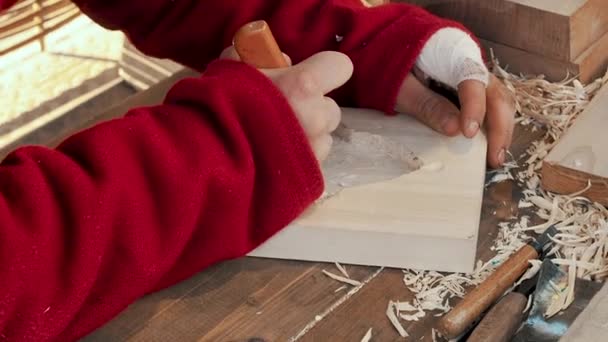 Майстер вирізав тарілку для випічки пряників та печива з дерева ножем. Художній різьбяр по дереву робить різьблення по дереву. Деталь робочих рук. Скульптор створює скульптуру. Традиційне ремесло — стокове відео