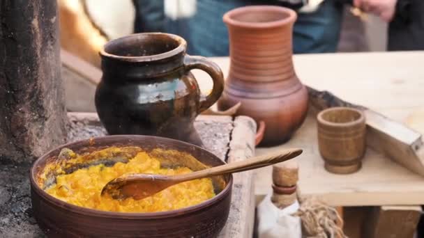 Cooking pumpkin porridge on fire. Food to be cooked in a in a clay pan outdoor clay oven. A dish in a wood burning stove. Reconstruction of medieval life concept — Stock Video