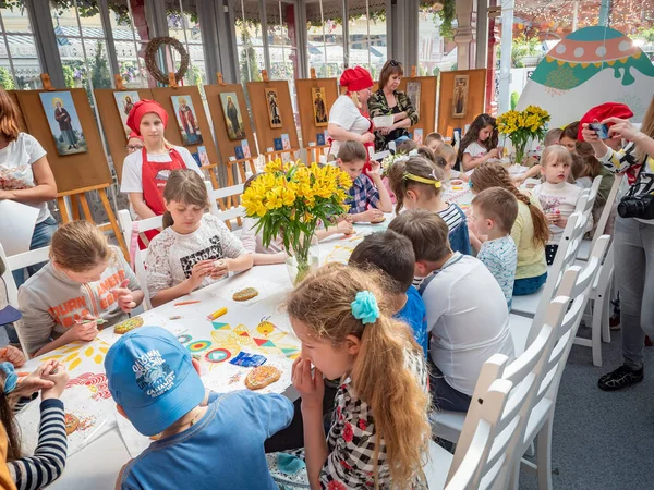 Oroszország, Moszkva 2019. április 26.: Mesterkurzus a Manezhnaya téren gyerekeknek húsvétkor. Óvodás gyerekek egy mézeskalács dekorációról szóló mesterkurzuson. A gyermekek felnőttek felügyelete mellett tanulnak — Stock Fotó