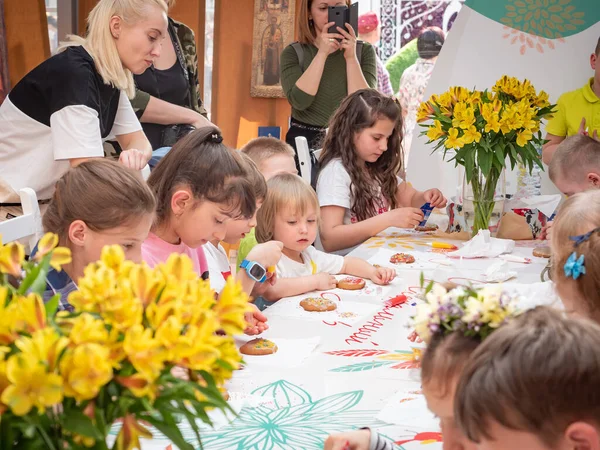 Oroszország, Moszkva 2019. április 26.: Mesterkurzus a Manezhnaya téren gyerekeknek húsvétkor. Óvodás gyerekek egy mézeskalács dekorációról szóló mesterkurzuson. A gyermekek felnőttek felügyelete mellett tanulnak — Stock Fotó