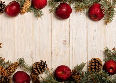 Noel elma ve beyaz tahta üzerinde koniler ile çam dalları 