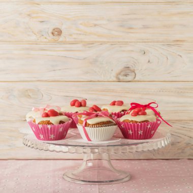 Pembe şeker ve kurdele ile süslenmiş beyaz buzlanma ile cupcakes.