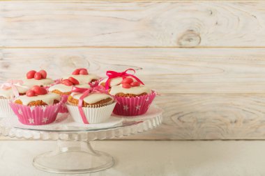 Pembe şeker ve kurdele ile süslenmiş beyaz buzlanma ile cupcakes.