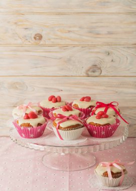 Pembe şeker ve kurdele ile süslenmiş beyaz buzlanma ile cupcakes.