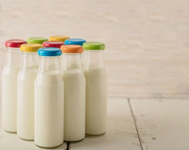 Dokuz cam süt şişesi çok renkli kapaklar.