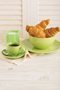 Kahve süt ve kruvasan hafif ahşap arka plan üzerinde.