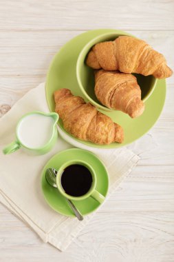 Kahve süt ve kruvasan hafif ahşap arka plan üzerinde.