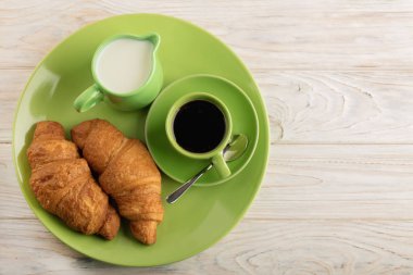 Kahve süt ve kruvasan hafif ahşap arka plan üzerinde. 