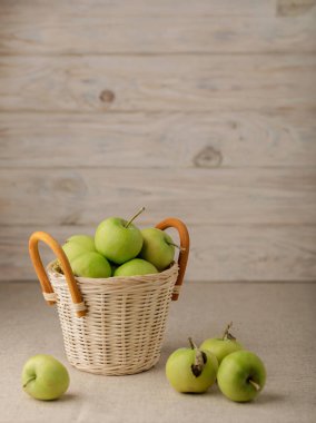 Hafif ahşap bir arka plan üzerinde bir hasır sepet içinde yeşil elma. 