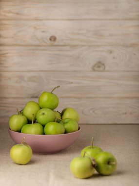 Ahşap açık renkli leylak bir tabağa yeşil elma. 