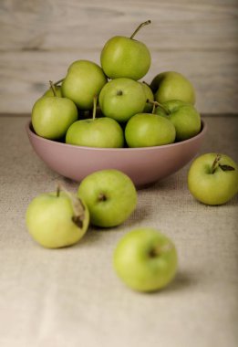 Ahşap açık renkli leylak bir tabağa yeşil elma. 