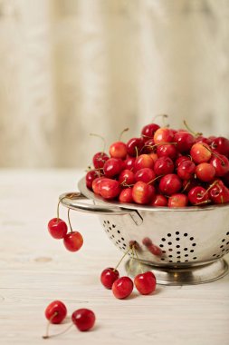 Hafif ahşap arka plan üzerinde bir kevgir içinde kiraz. 