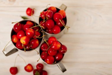 Hafif ahşap arka plan üzerinde metal bardağı kiraz. 