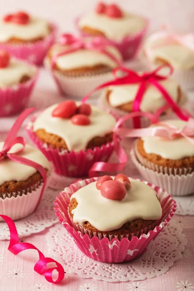 Pembe şeker ve kurdele ile süslenmiş beyaz buzlanma ile cupcakes.