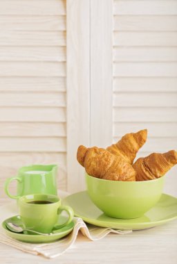 Kahve süt ve kruvasan hafif ahşap arka plan üzerinde. 