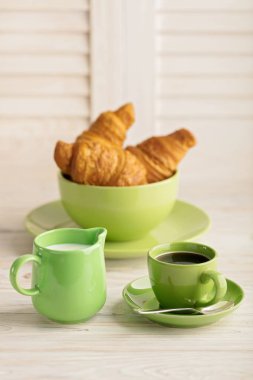 Kahve süt ve kruvasan hafif ahşap arka plan üzerinde. 