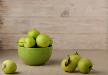 Ahşap açık arka planı yeşil bir tabağa yeşil elma.