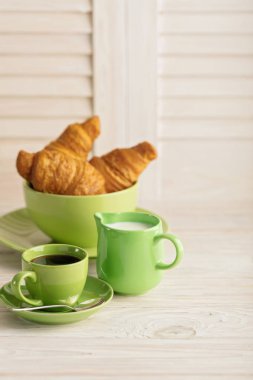 Kahve süt ve kruvasan hafif ahşap arka plan üzerinde.