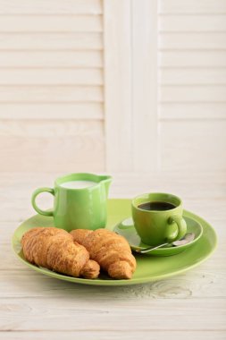 Kahve süt ve kruvasan hafif ahşap arka plan üzerinde. 