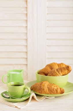 Kahve süt ve kruvasan hafif ahşap arka plan üzerinde.