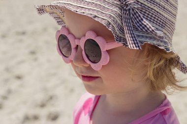 Pembe güneş gözlüğü denizde küçük komik kız (3 yaşında). 