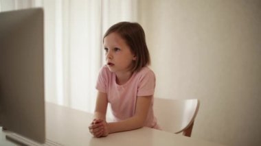 Küçük komik kız (8 yaşında) bilgisayarda video izliyor. Seçici odak.