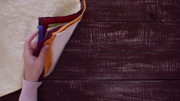 Les mains féminines empilent des serviettes en lin de différentes couleurs sur une vieille table en bois .