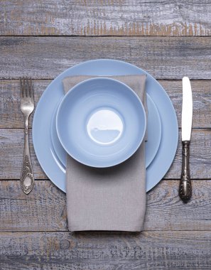 Mavi tabaklar, eski gri ahşap arka planda peçete ve çatal bıçak takımı