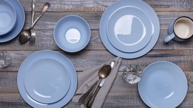 Mavi tabaklar, eski gri ahşap arka planda peçete ve çatal bıçak takımı