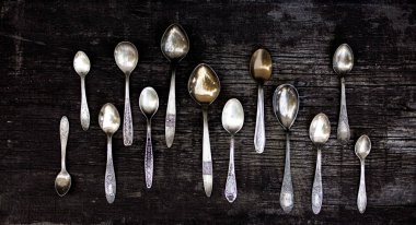 Eski bir ahşap arka planda kaşıklar, çatallar ve bıçaklar..