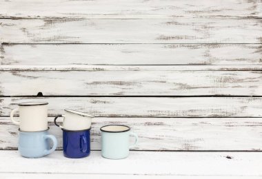 Eski ahşap arka planda retro tarzda emaye kupalar. 