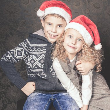 Komik çocuklar Noel ağacının yanında oturuyor. Santa şapka giymiş.