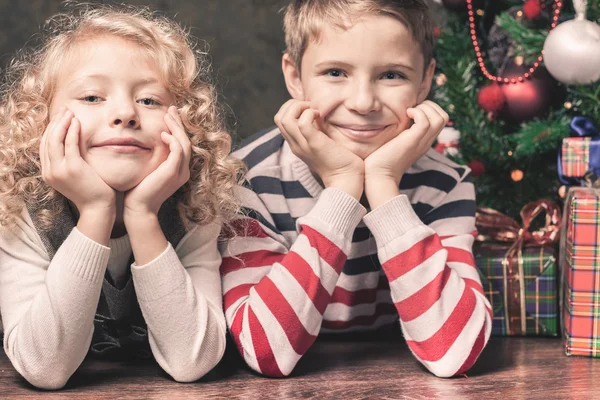 Crianças felizes deitadas no chão debaixo da árvore de Natal . — Fotografia de Stock